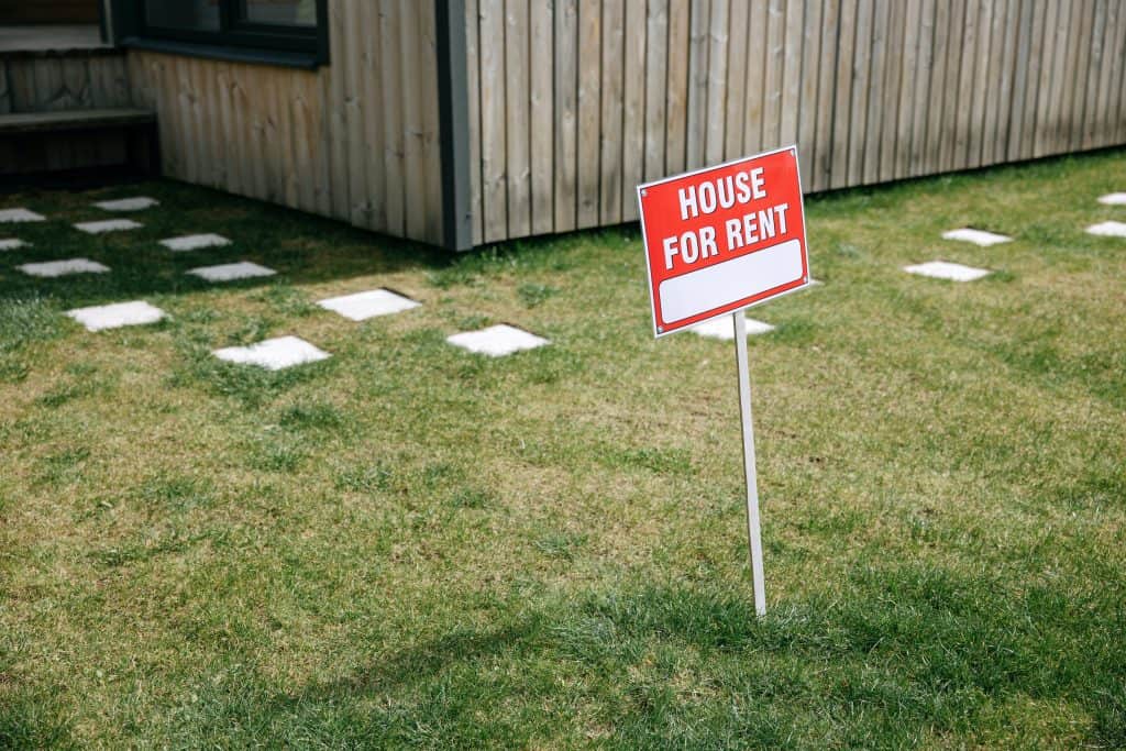 A rental property sign in front of a house.