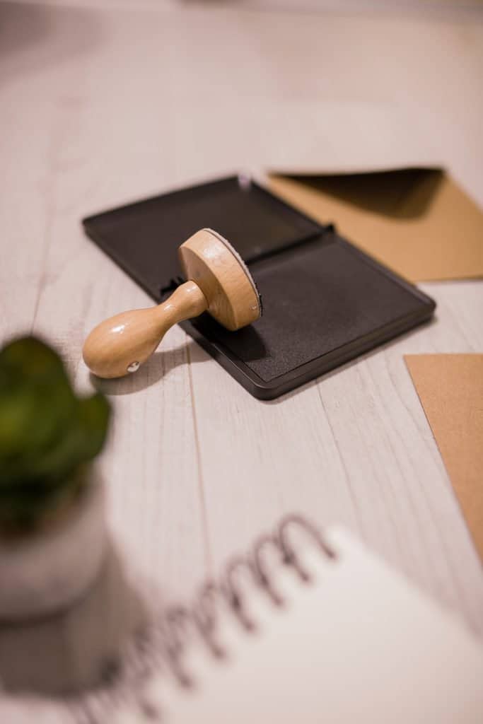 A wooden stamp on a desk next to a notebook and a plant, symbolizing the bonds.